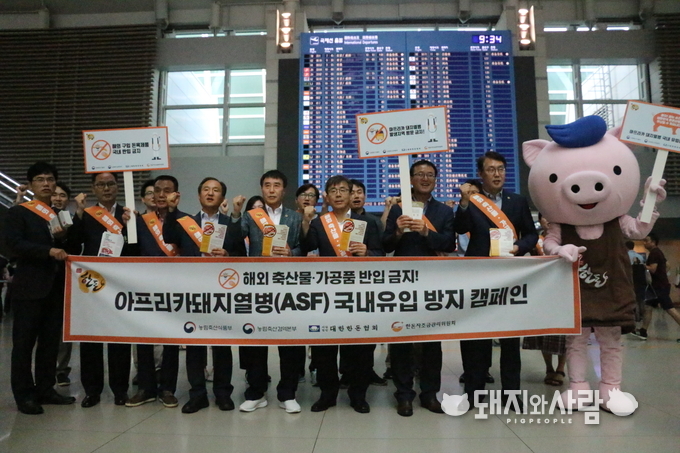 (좌측 4번째부터) 농림축산식품부 장재홍 검역정책과장, 대한한돈협회 하태식 회장, 농림축산검역본부 남태헌 인천공항지역본부장 등 관계자 약 20여명이 아프리카 돼지열병(ASF) 국내 유입 방지를 위해 인천국제공항에서 해외여행객 대상 캠페인을 펼치고 있다.